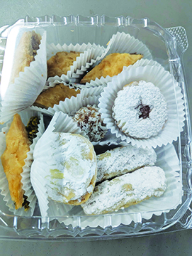 a variety of middle eastern cookies and sweets filling a plastic take away container
