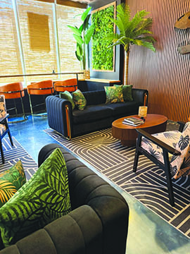 inside of restaurant, corner area with couches and chairs, plants and tropical patterns