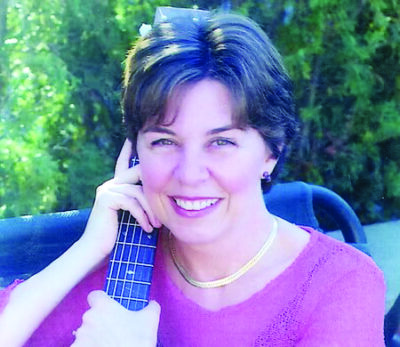 short haired woman sitting outside, holding guitar