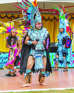 men and women in traditional regalia, ready to dance on stage