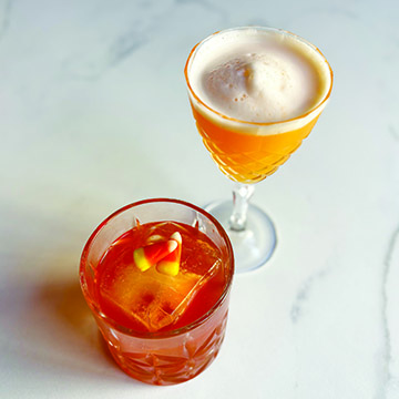 a stemmed glass and a short ball glass filled with cocktails