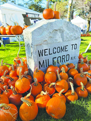 image of carved stone with words "Welcome to Milford" surrounded by sugar pumpkins