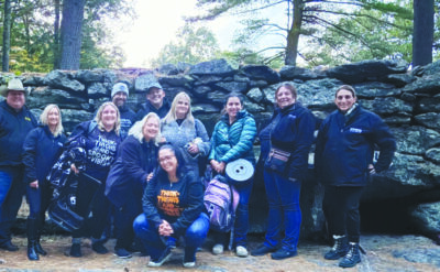 group of people standing in front of stone wall at dusk