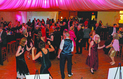 people in evening wear dancing on hardwood floor at event