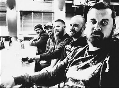5 men sitting at counter, black and white promo photo