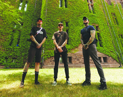 three young men standing in front of ivy covered brick building